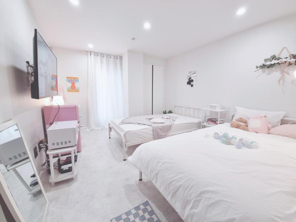 Dieses weiße Zimmer verfügt über 2 Betten und einen TV. in der Unterkunft Urban Stay Anyang in Anyang