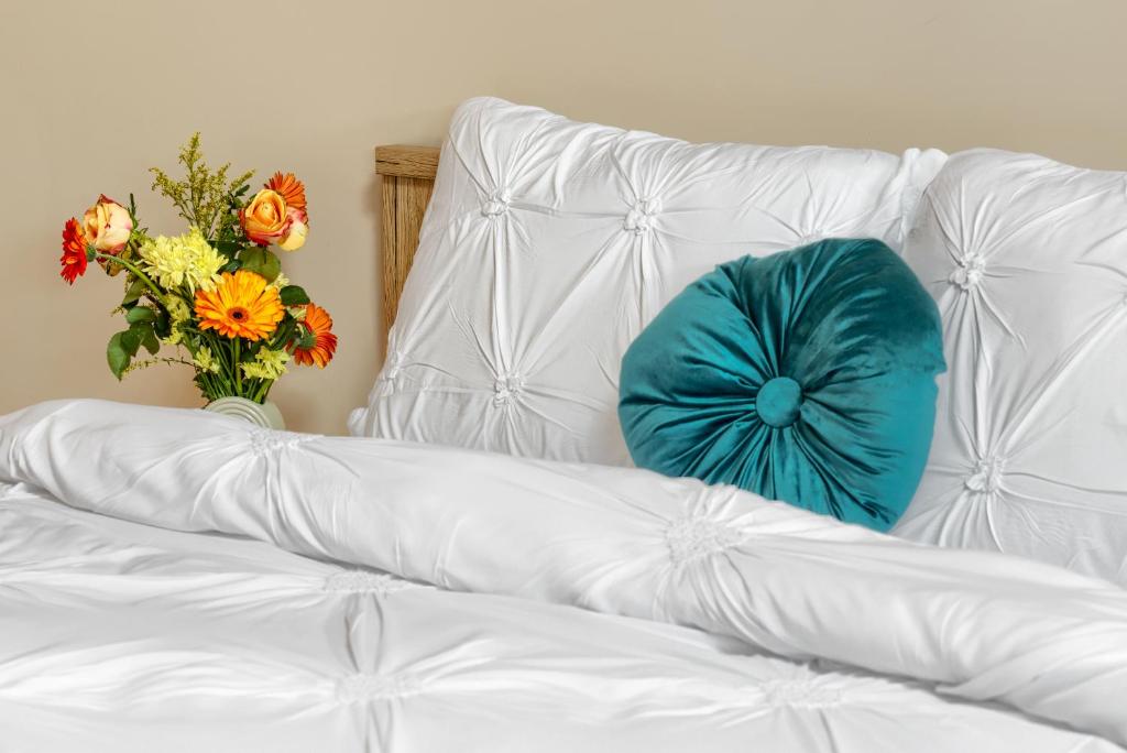a white couch with a blue pillow and a vase of flowers at ARI Central Grand SkyView - Family Apartment in Arad