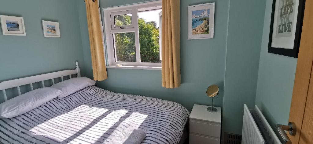 1 dormitorio con cama y ventana en Chy Lowen Private rooms with kitchen, dining room and garden access close to Eden Project & beaches en Saint Blazey