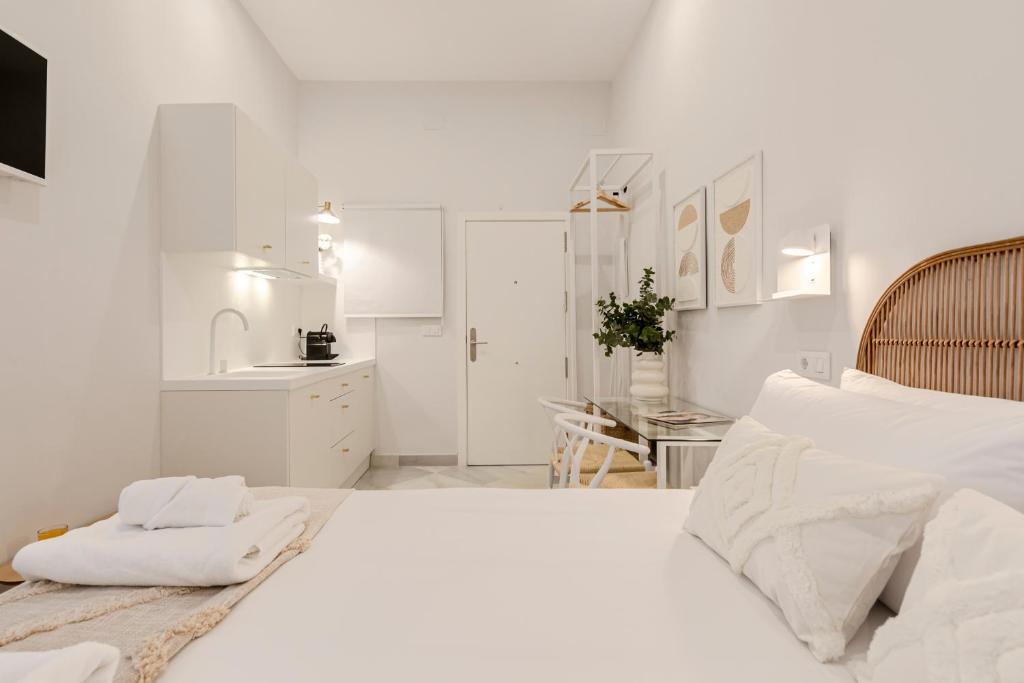 een witte slaapkamer met een groot bed en een keuken bij ISG Apartments Cuna 10 in Sevilla