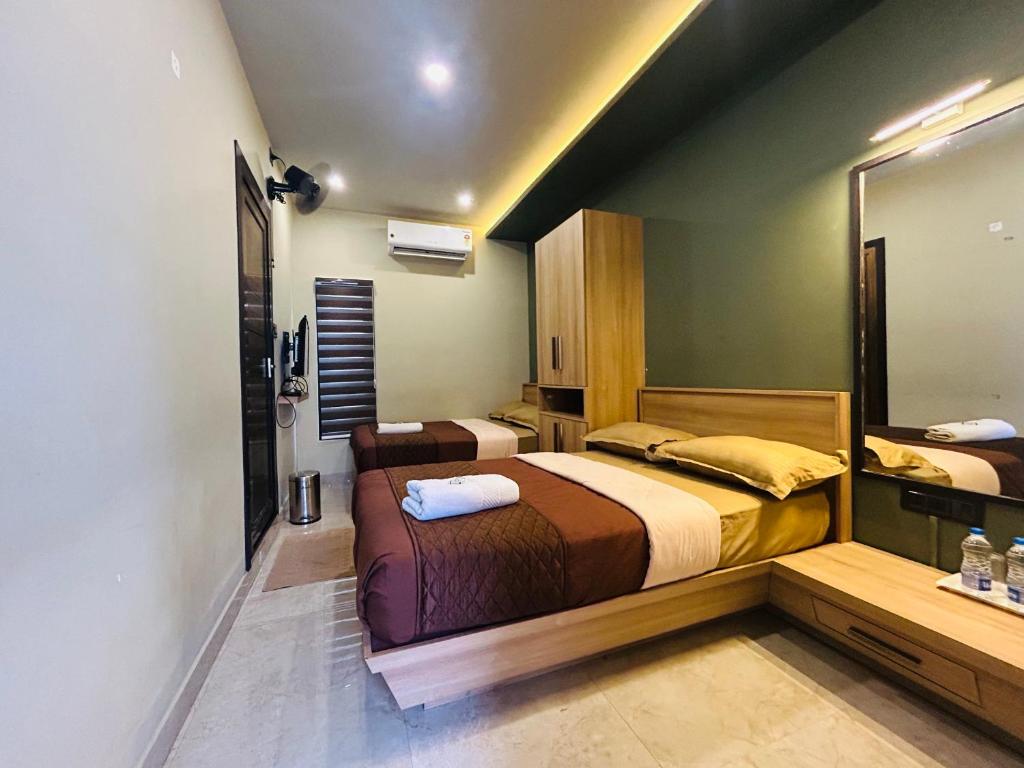 a bedroom with two beds and a large mirror at NIDRA INN in Kozhikode