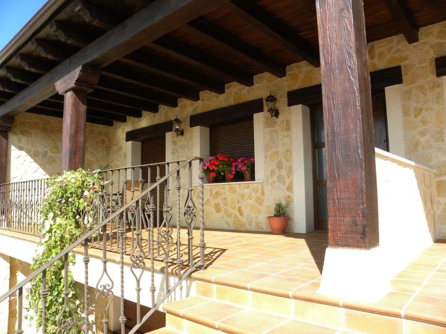 a porch of a house with a staircase and flowers at Casa Rural Paula in Zarzuela del Monte