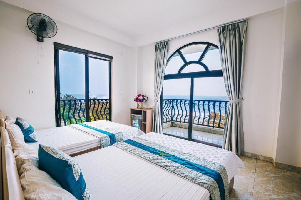 two beds in a room with a large window at Hương Lý Hotel in Sầm Sơn