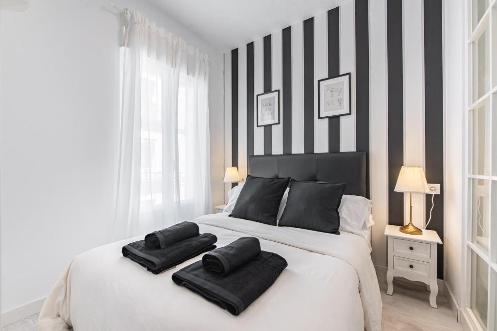 a bedroom with a large white bed with black and white stripes at Vacavic Plaza Mayor apartament in Madrid