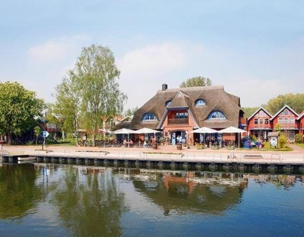 a restaurant with a thatched building next to a river at Appartement in Plau Am See mit Garten und Grill in Plau am See
