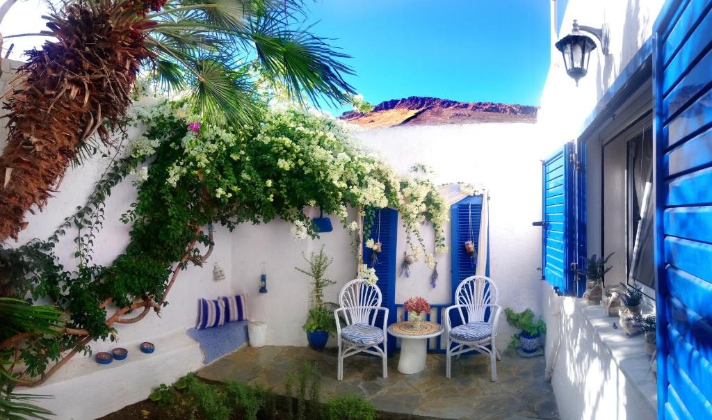 une terrasse avec des chaises blanches, une table et un palmier dans l'établissement Small traditiional home near the shops and restaurants in Korissia, Kea, à Ioulída