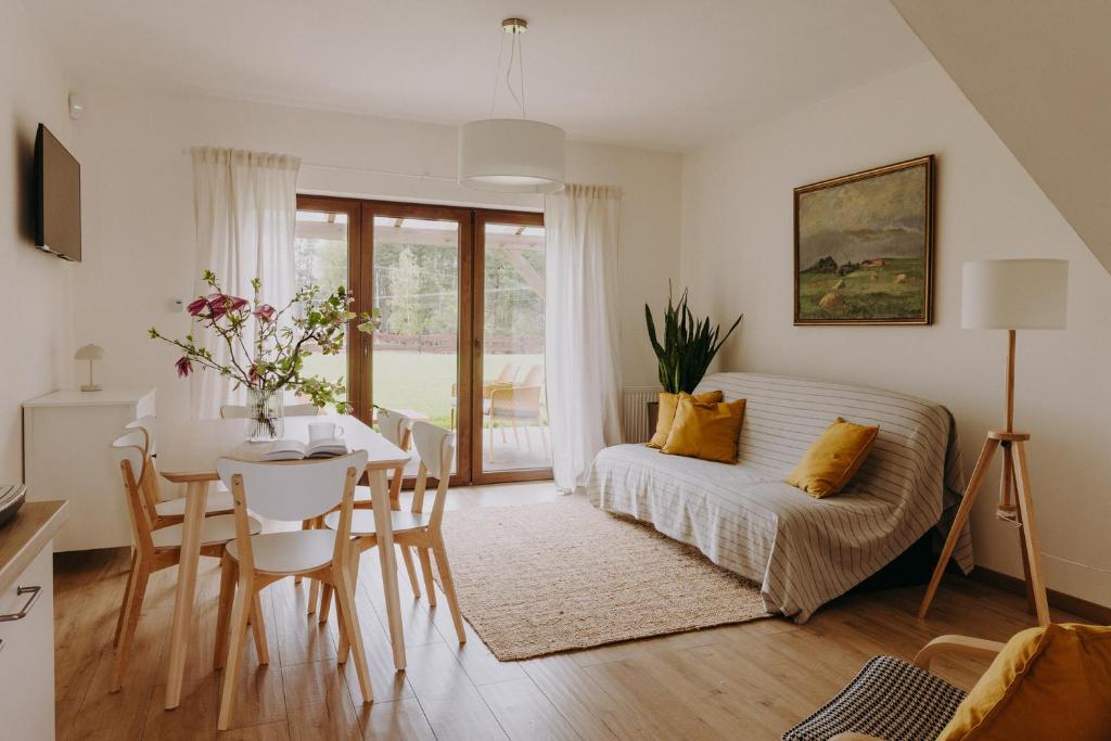 a living room with a table and a white couch at OSADA GRZYBOWSKI MŁYN apartamenty z dużym ogrodem KAISERÓWKA in Grzybowo