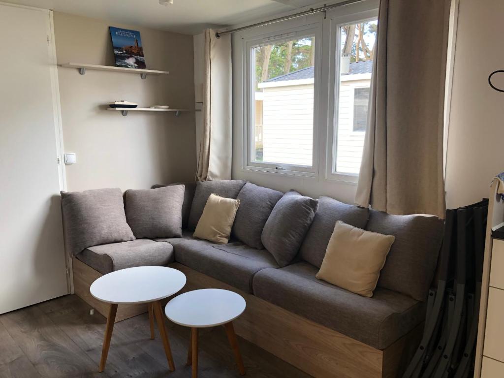 sala de estar con sofá y 2 mesas en Mobil Home vue mer, en Quiberon