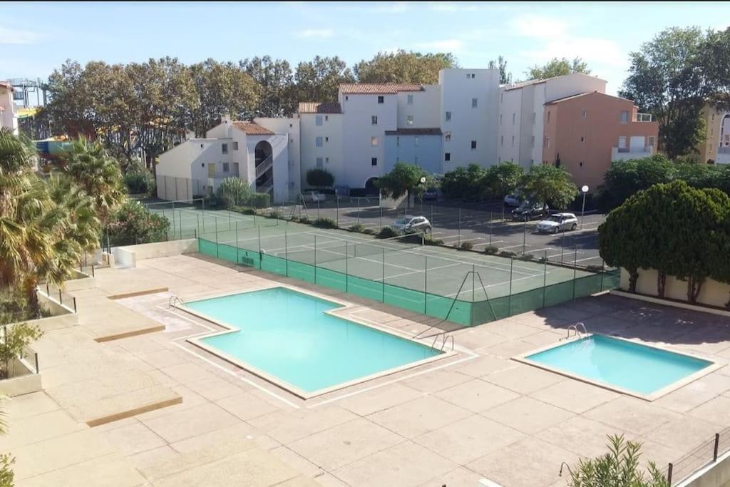 deux piscines sur un patio avec un court de tennis dans l'établissement Apt T2 bis, 5p secteur Richelieu avec terrasse, piscine, tennis, parking privé, au Cap d'Agde