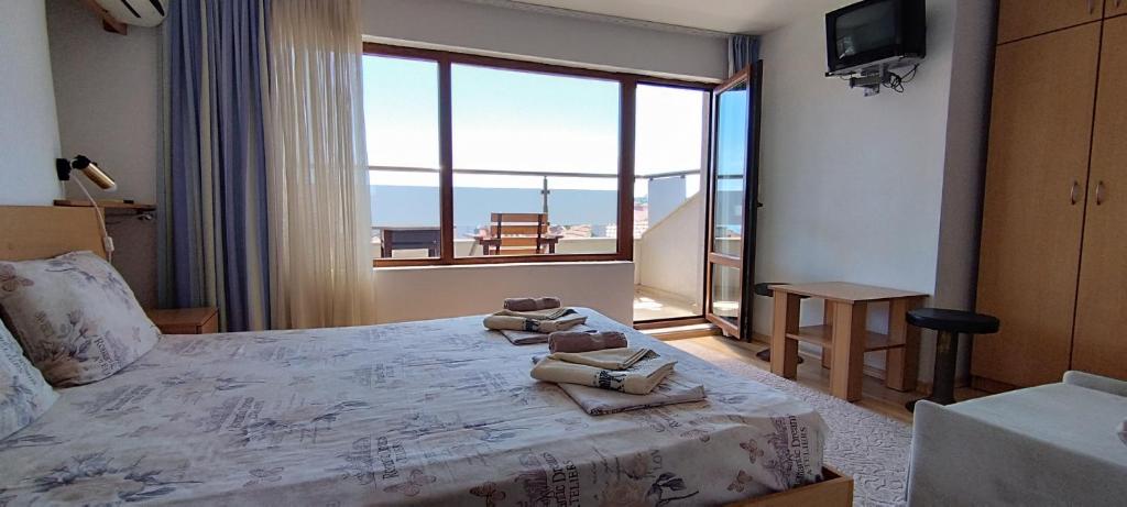 a hotel room with a bed with a large window at Anchors Guest House in Sozopol