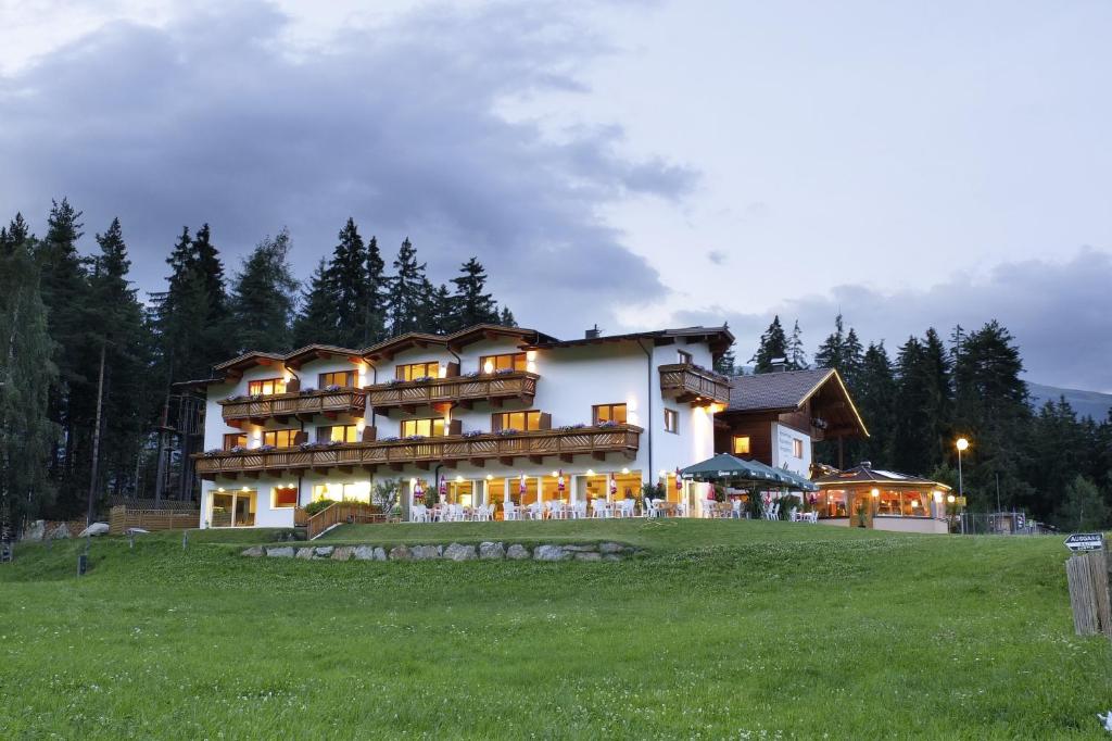 ein großes Gebäude auf einem grünen Feld in der Unterkunft Familienhotel Moos-Alm in Lienz