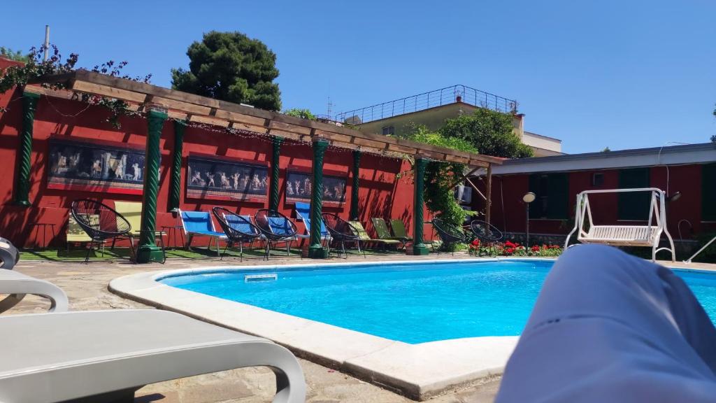 uma piscina com cadeiras e um edifício em La Villa Franca Pompeii em Pompeia