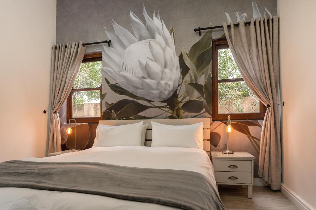 a bedroom with a large white flower mural on the wall at Sixteen Guesthouse on Main in Hermanus