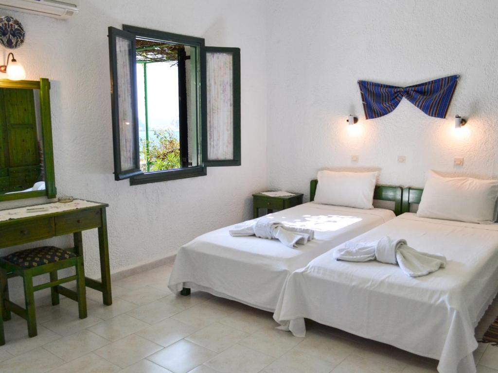 a bedroom with two beds and a desk and a mirror at Hotel Finiki View in Foiníkion