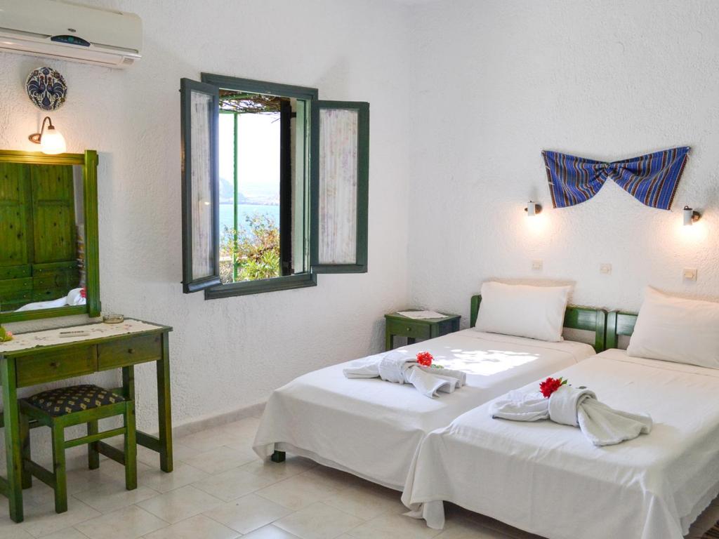 two beds in a room with a desk and a mirror at Hotel Finiki View in Foiníkion