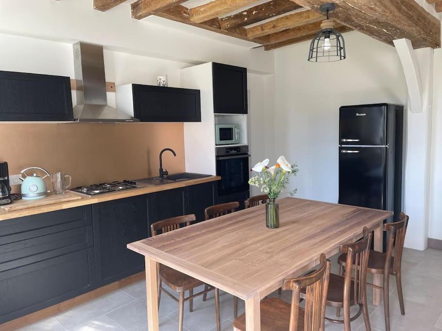 a kitchen with a wooden table and a black refrigerator at Maison bord de Loire in Saint-Clément-des-Levées