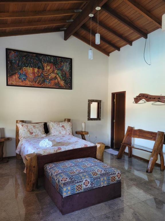 a bedroom with a bed and a bench in it at Brisa da Serra Hotel Pousada Pirenopolis in Pirenópolis