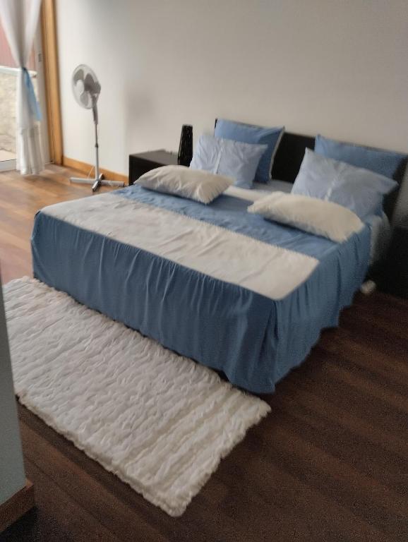 a large bed with blue and white sheets and pillows at O Cantinho do Arnaldo in Viana do Castelo