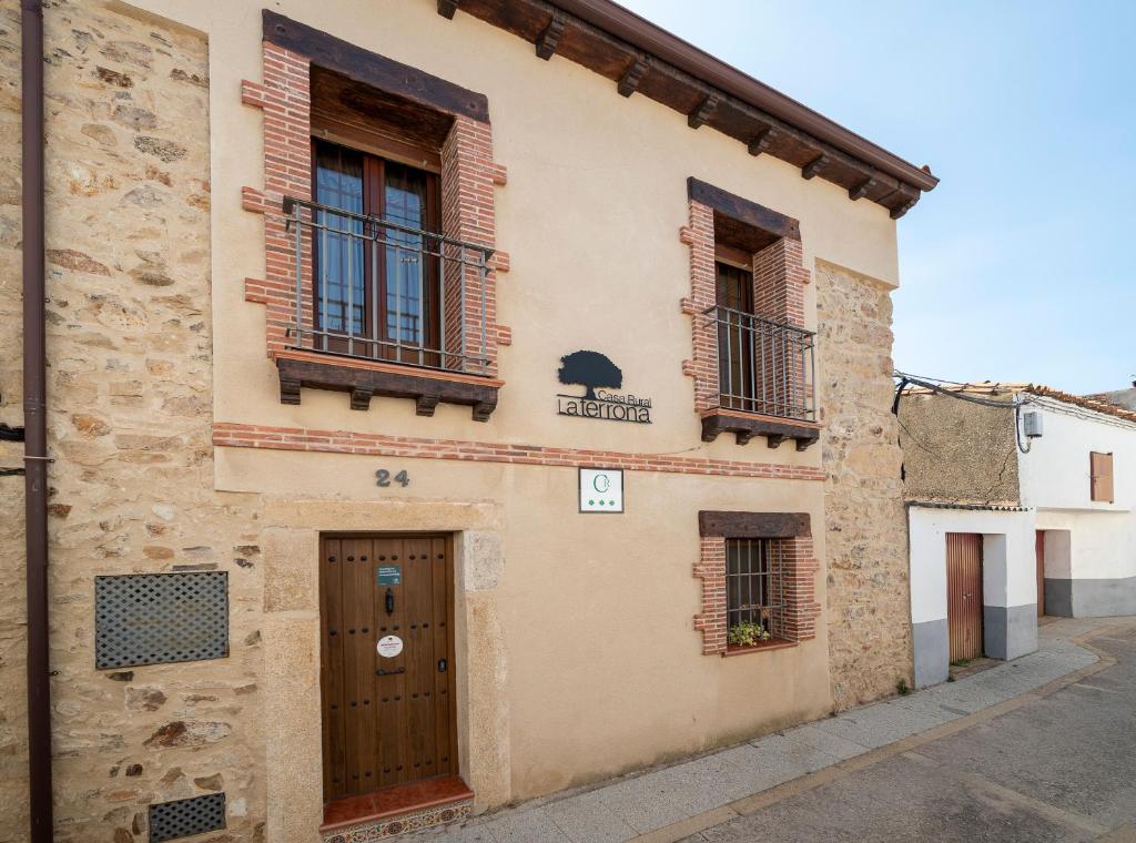 un edificio con dos ventanas y una puerta en Casa Rural La TERRONA en Zarza de Montánchez