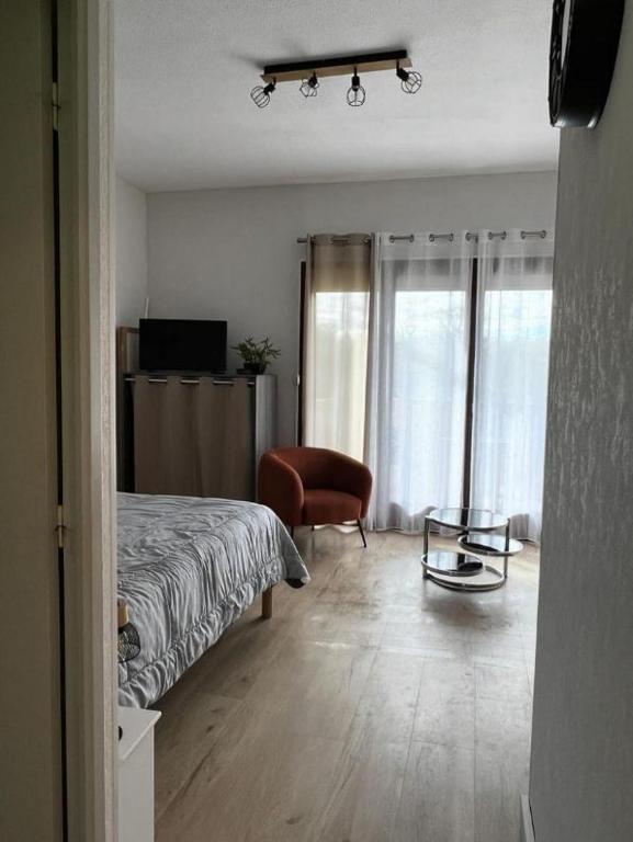 une chambre avec un lit, une chaise et une table dans l'établissement BEAULIEU T1BIS wifi parking 200m des thermes, à Cazaubon