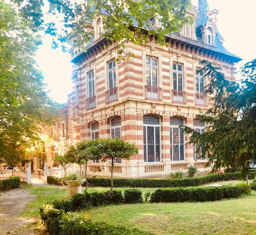un gran edificio de ladrillo con árboles delante de él en Château de La Prade, en Narbona