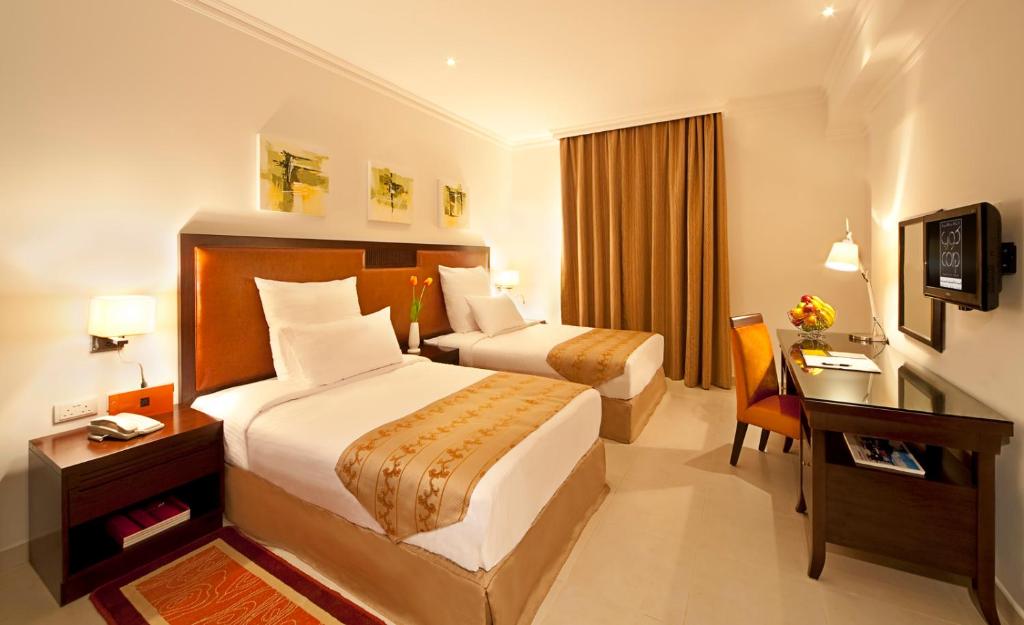 een hotelkamer met 2 bedden en een bureau bij Corp Hotel Apartments and Spa in Doha