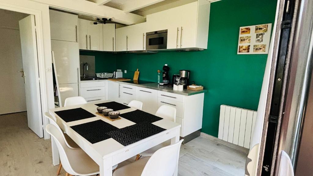 een keuken met een tafel en stoelen en een groene muur bij 800m mer- La maison sous les pins-rénovée 2024 in Neufchâtel-Hardelot