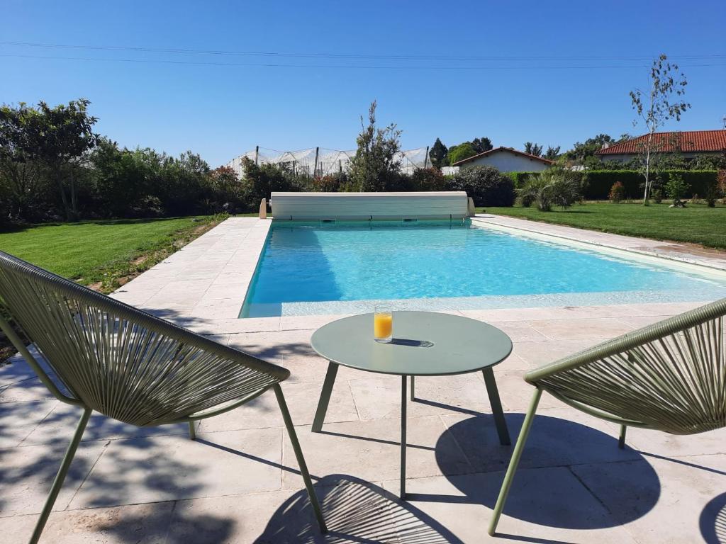 - deux chaises et une table à côté de la piscine dans l'établissement Petit coin de paradis, calme et confort garantie !, à Montauban