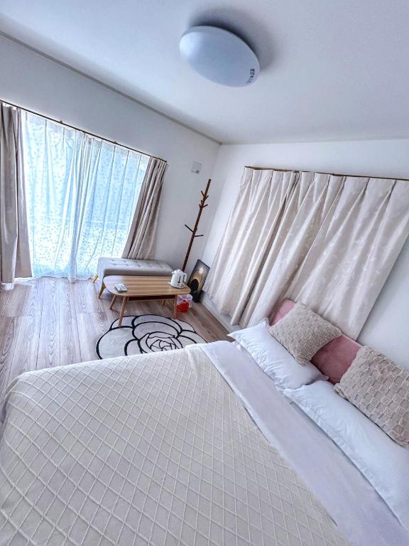 a bedroom with a large white bed and a window at Sunflower 民泊 in Tokyo