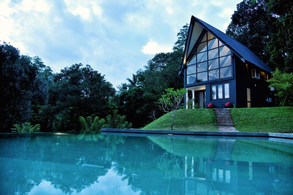 a house on top of a hill next to a body of water at The Country House Chalets in Galle