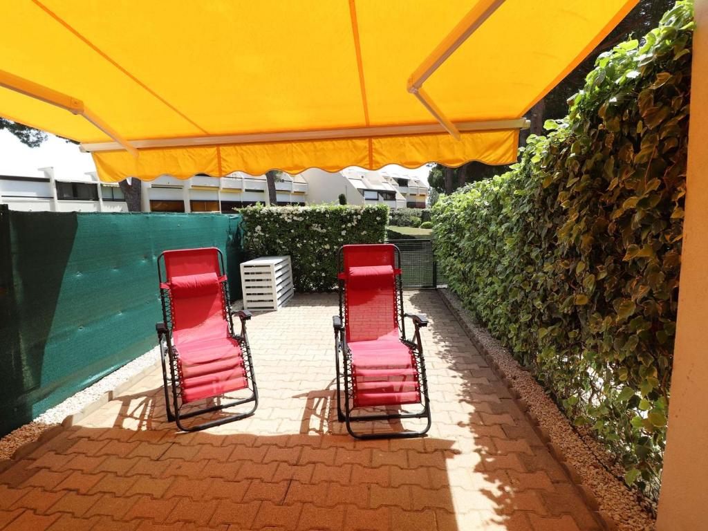 trois chaises sous un parasol sur une terrasse dans l'établissement Charmant T2 Cabine climatisé avec terrasse, parking à 100m de la plage - FR-1-307-111, au Grau-du-Roi