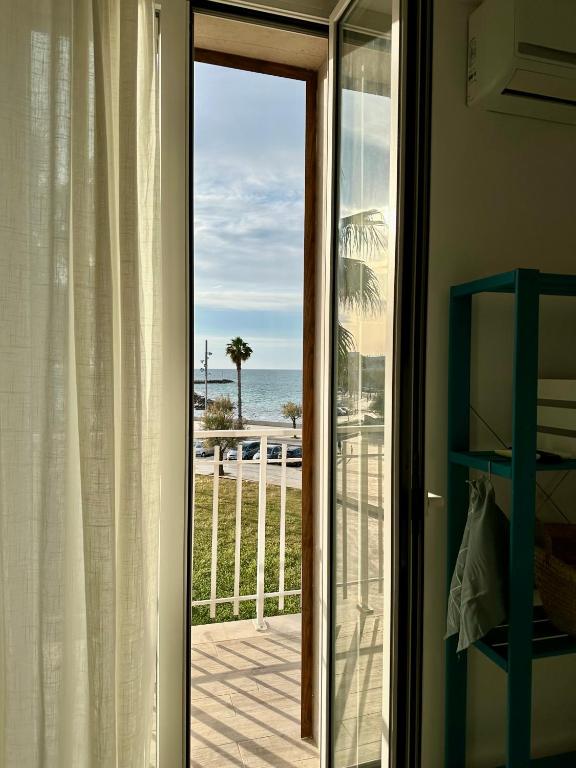 a sliding glass door with a view of the ocean at Maris Apartment by Tenuta Pinto in Mola di Bari