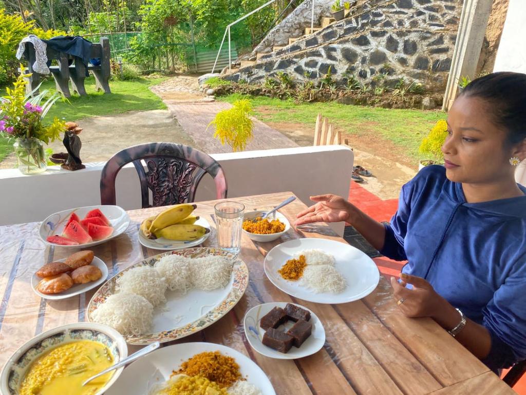 a woman sitting at a table with plates of food at Ella Willow Cottage in Ella