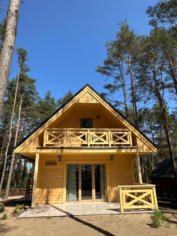a cabin in the woods with a large deck at Domek wypoczynkowy Sosenka z sauną i jacuzzi in Ocypel