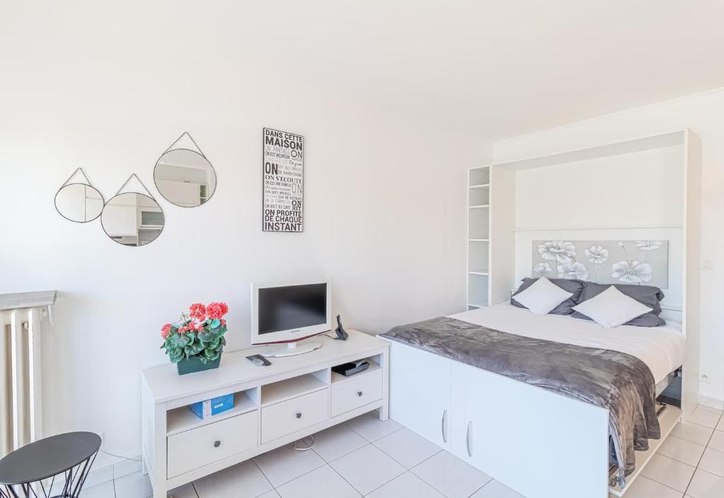 ein weißes Schlafzimmer mit einem Bett und einem Schreibtisch mit einem TV in der Unterkunft Nice Studio Near The Sea Roquebrune Cap Martin in Roquebrune-Cap-Martin