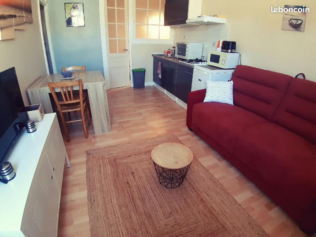 un salon avec un canapé rouge et une table dans l'établissement Appartement Les Cozettes, à La Bourboule