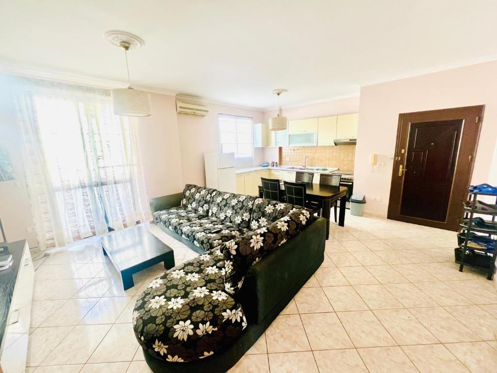 a living room with a green couch and a kitchen at Lovely 3-bedroom rental unit in Durrës in Durrës