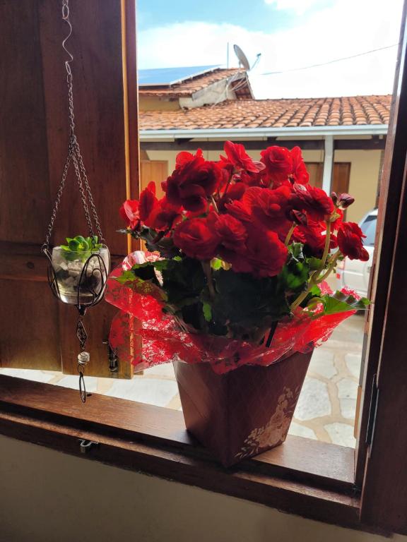 a vase of red roses sitting on a window sill at Brisa da Serra Hotel Pousada Pirenopolis in Pirenópolis