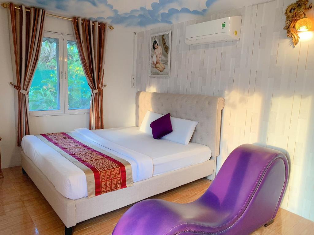 ein Schlafzimmer mit einem Bett und einem lila Stuhl in der Unterkunft NGỌC HƯNG HOTEL in Vĩnh Long