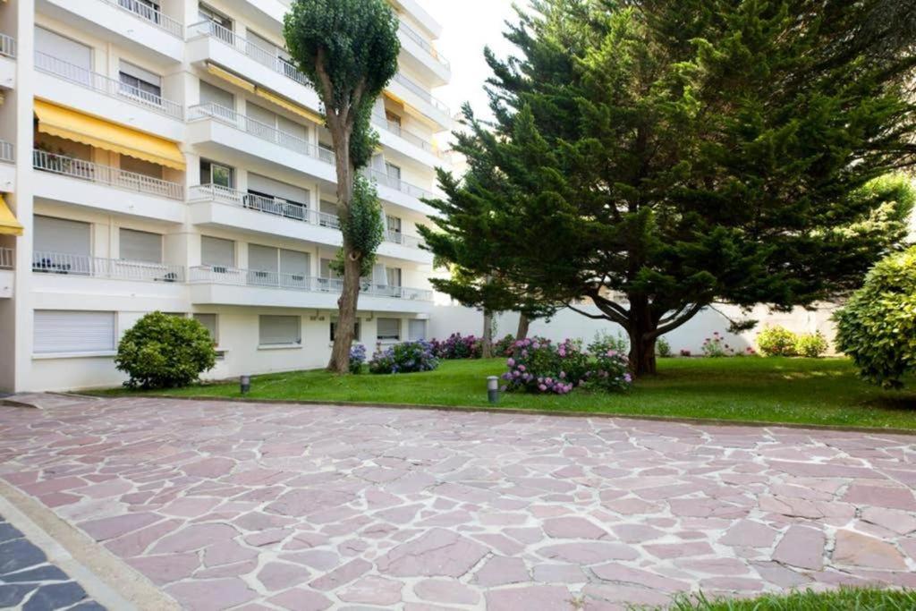 a large apartment building with trees and a stone driveway at Studio Sunset Biarritz in Biarritz