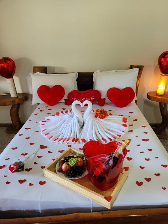 a bed with hearts and a plate of food on it at Brisa da Serra Hotel Pousada Pirenopolis in Pirenópolis
