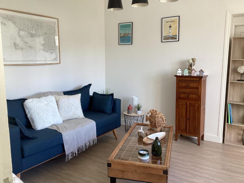 ein Wohnzimmer mit einem blauen Sofa und einem Tisch in der Unterkunft Ker LN in Saint-Nazaire