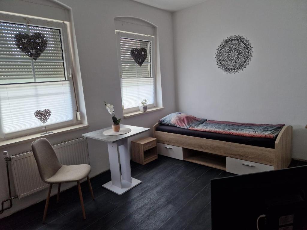 um quarto com uma cama, uma mesa e 2 janelas em Monteurzimmer und Pension - Ampfurth em Oschersleben