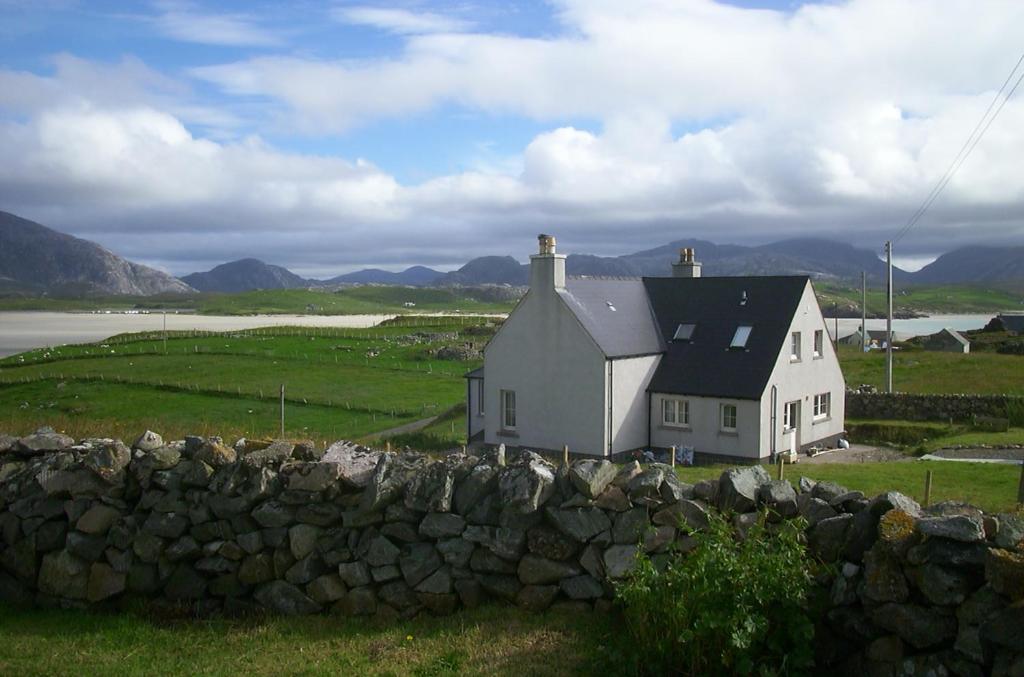 een wit huis in een veld met een stenen muur bij Airebroc House in Uig