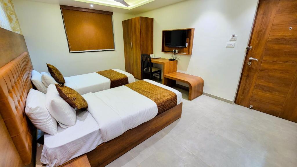 a hotel room with two beds and a television at Hotel Nova Pride in Rajkot