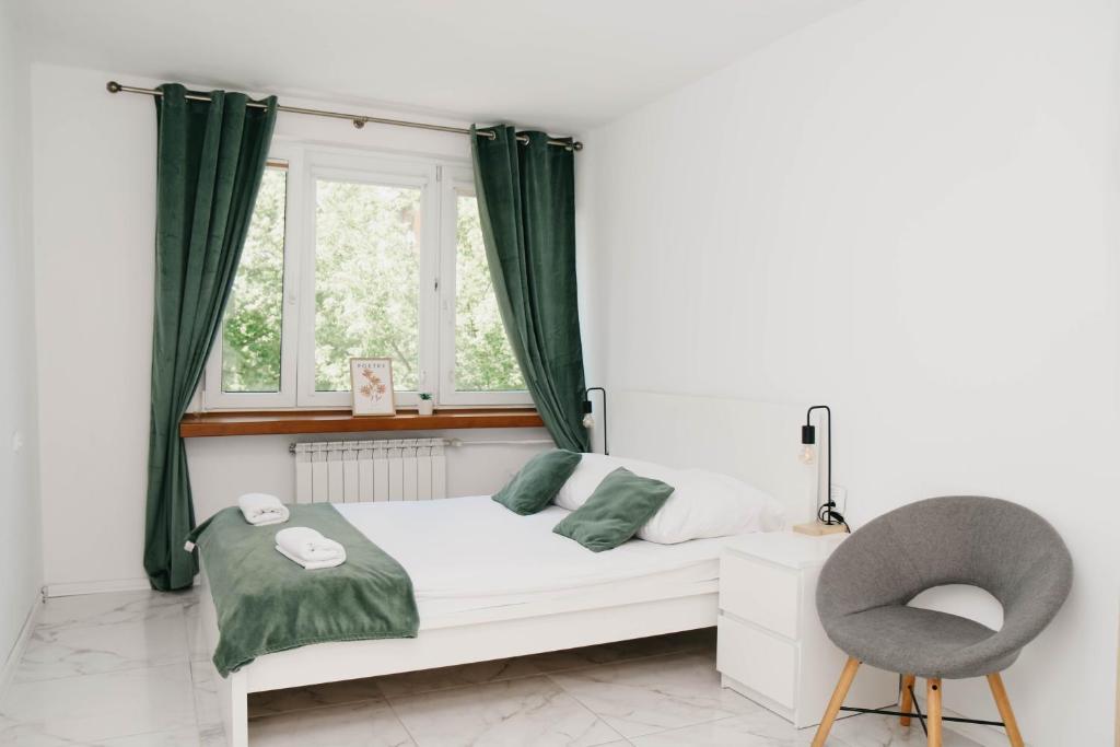 a bedroom with a bed and a chair and a window at Saska Kępa Luxe Apartment in Warsaw