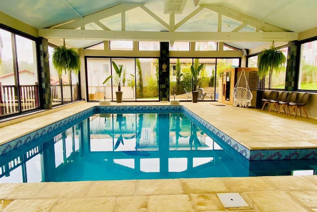 une piscine avec de l'eau bleue dans une maison dans l'établissement Maison avec piscine intérieure chauffée à 10min de Biarritz, à Ahetze