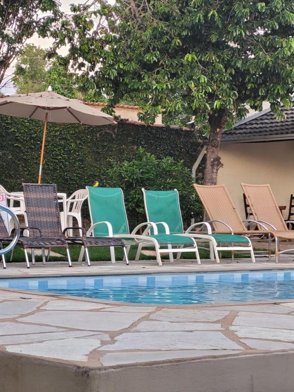 a group of chairs and an umbrella next to a pool at Brisa da Serra Hotel Pousada Pirenopolis in Pirenópolis