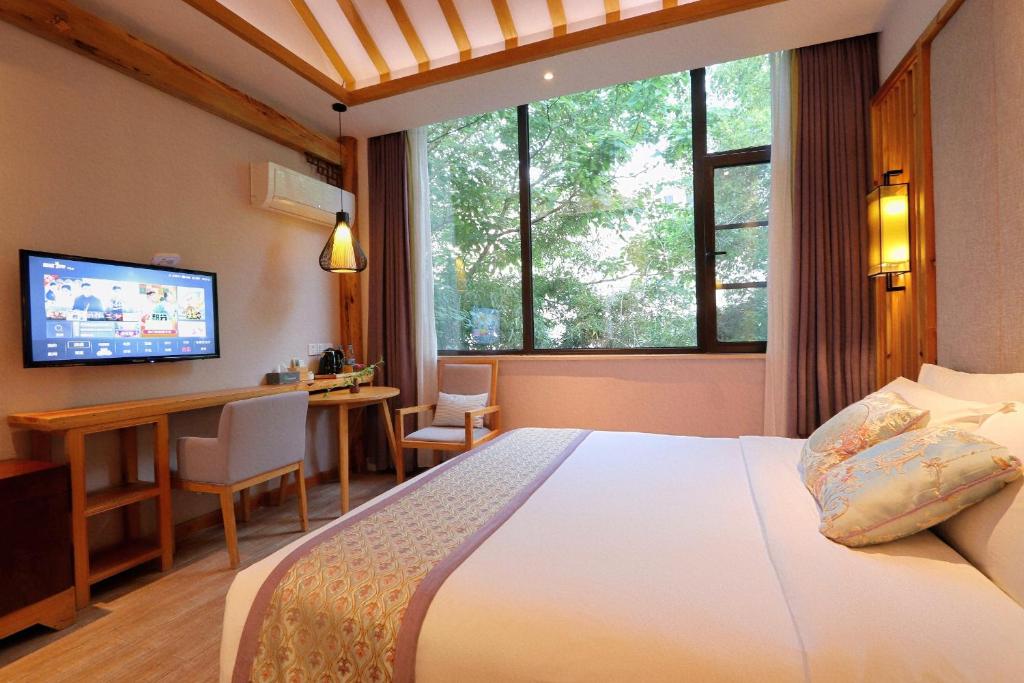 um quarto com uma cama, uma secretária e uma televisão em Mild Spring Boutique Hotel em Montanhas Huangshan