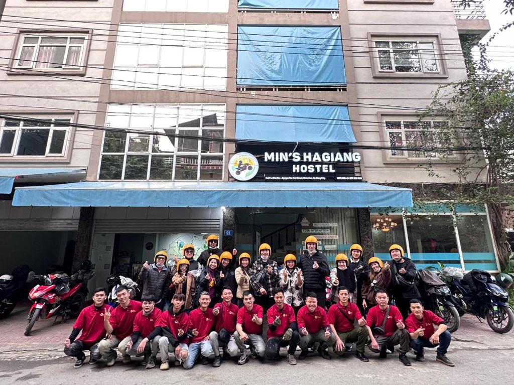 un grupo de personas posando para una foto frente a un edificio en Min's Ha Giang Hostel, en Ha Giang